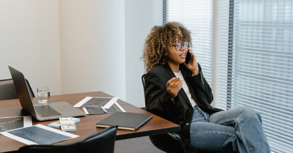A business analyst engaged in work, sitting at a desk with a laptop and graphs.
